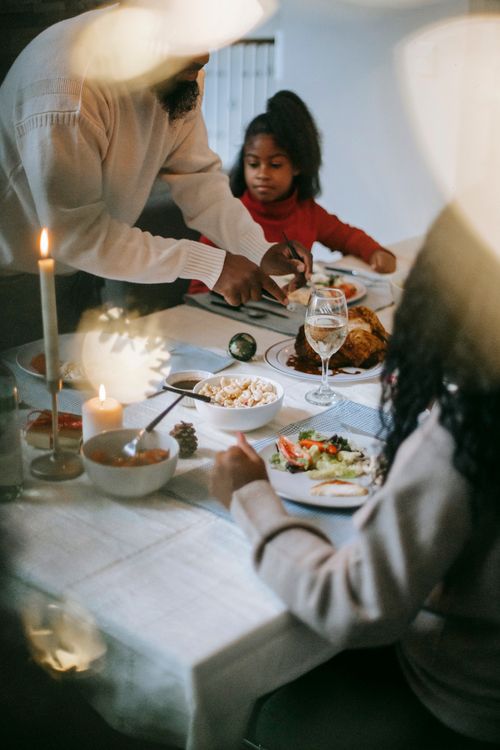 Free A family enjoys a cozy dinner with a warm candlelit atmosphere. Stock Photo