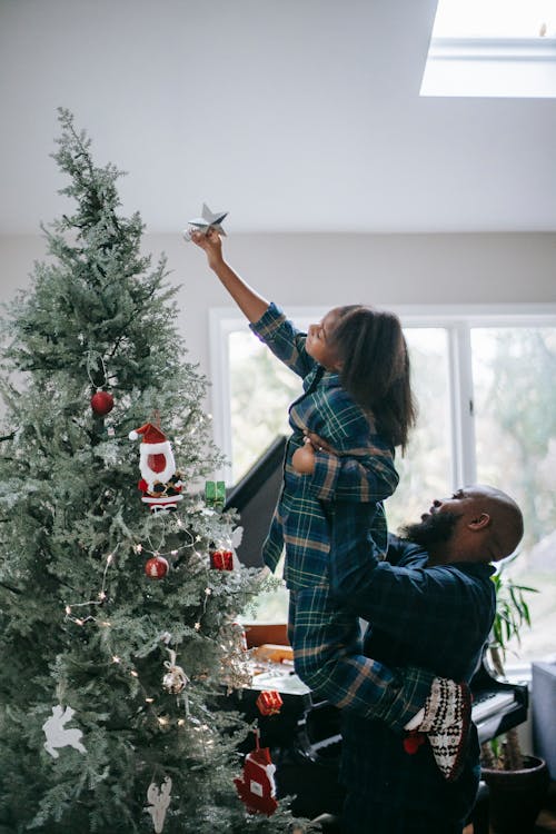 A Girl Putting a Star on Top of a Christmas Tree