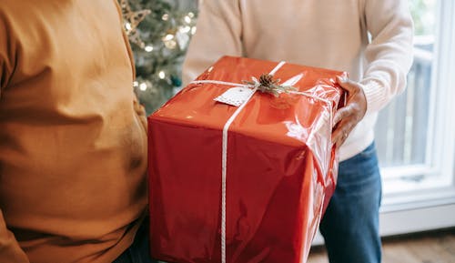 Free Crop anonymous African American father giving big present box to teen son during festive celebration at home Stock Photo