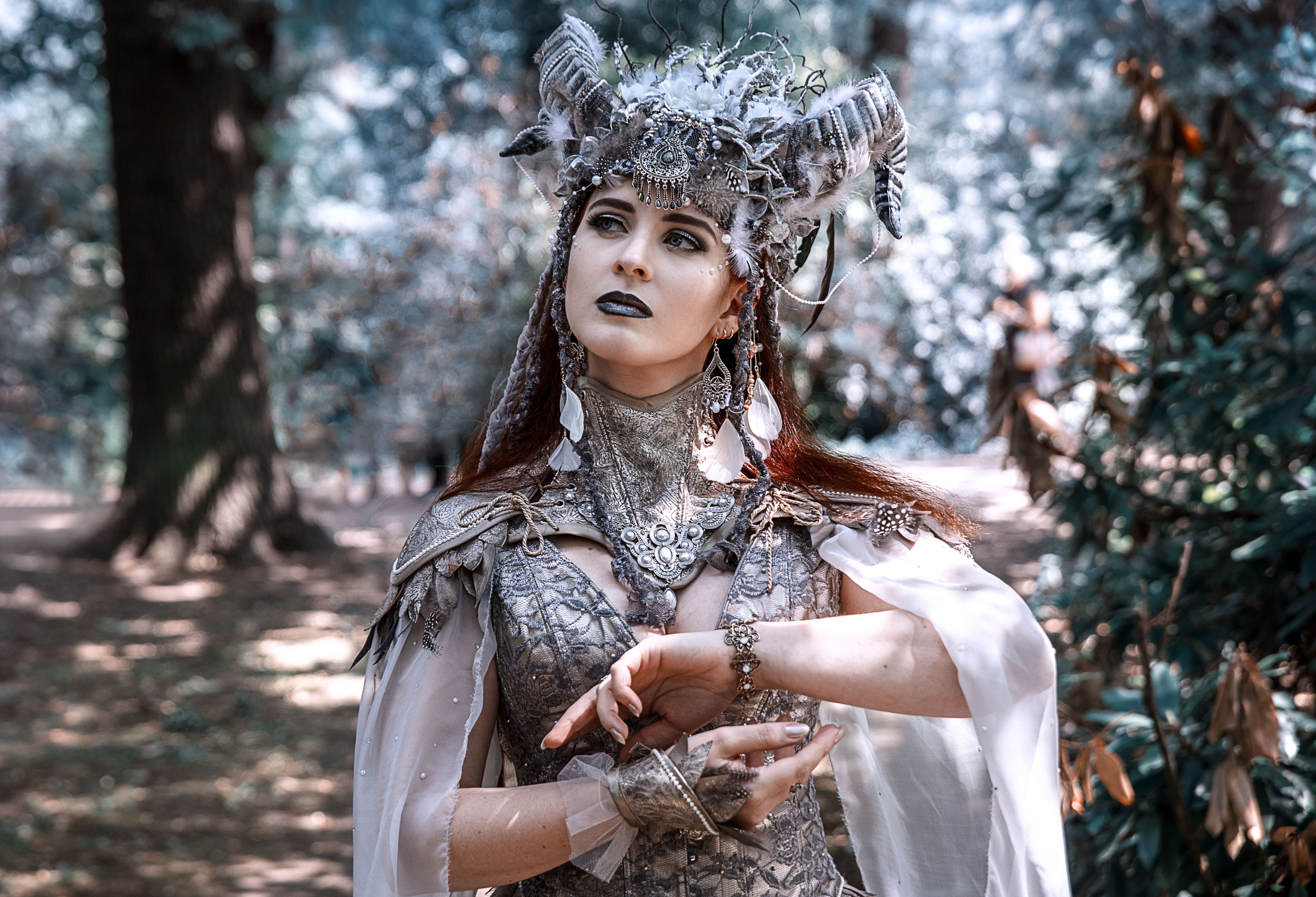 Woman in mystical costume posing gracefully in a serene forest setting.