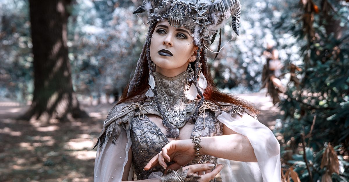 Woman in mystical costume posing gracefully in a serene forest setting.