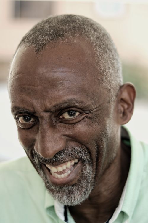 Free Happy mature African American male in casual clothing with short gray hair and beard looking at camera with toothy smile on blurred background Stock Photo