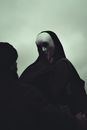 Black and white of anonymous man and anonymous person in white mask touching covered face