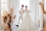 Happy Asian newlyweds standing in luxury wedding studio