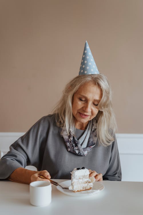 Photo of a Woman with a Party Hat Eating Cake