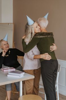 老年朋友们在室内戴着派对帽、带着礼物庆祝生日