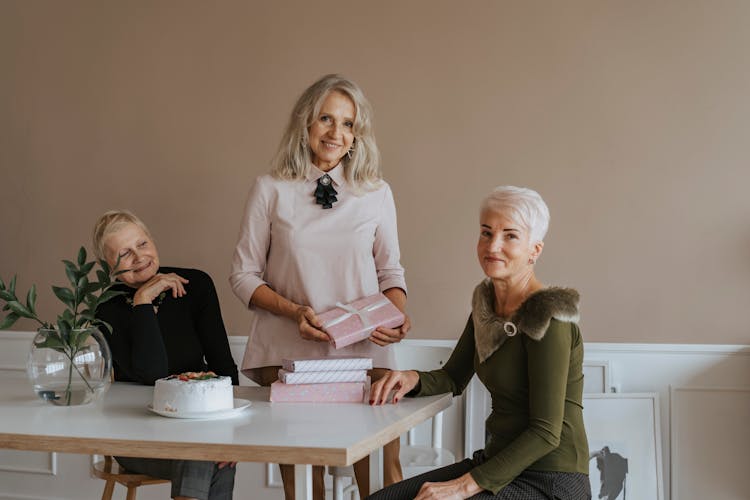 An Elderly Woman Holding A Gift Near Her Friends