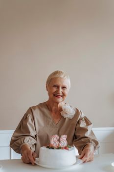 一位面带微笑的老年妇女拿着一个插着“65”蜡烛的蛋糕