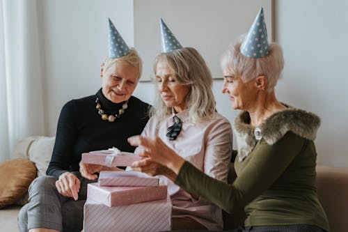 Free Friends in Party Hats Opening Birthday Presents Stock Photo