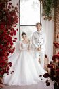 一对亚洲夫妇身着优雅婚纱，在鲜花盛开的房间里