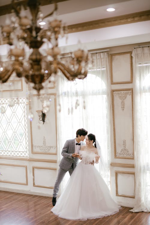Elegant Asian newlyweds in spacious ballroom