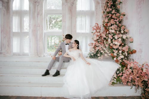 Bride and Groom Sitting on Stairs with a Flower Arrangement