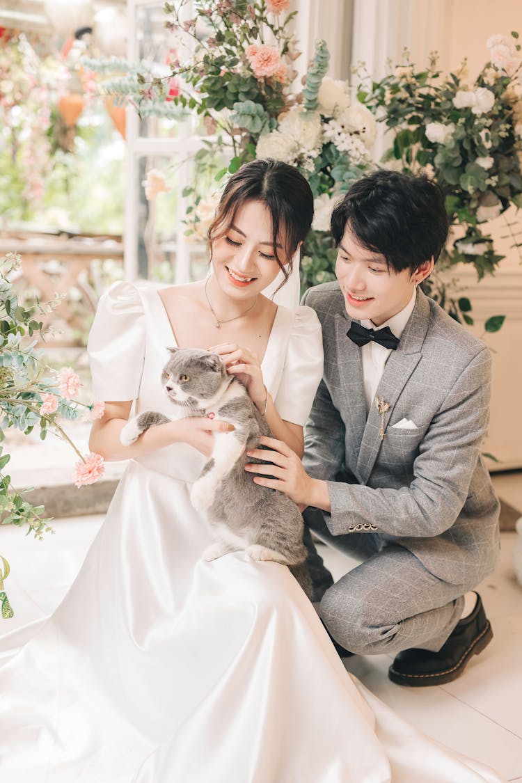 Happy Bride And Groom Cuddling Cat