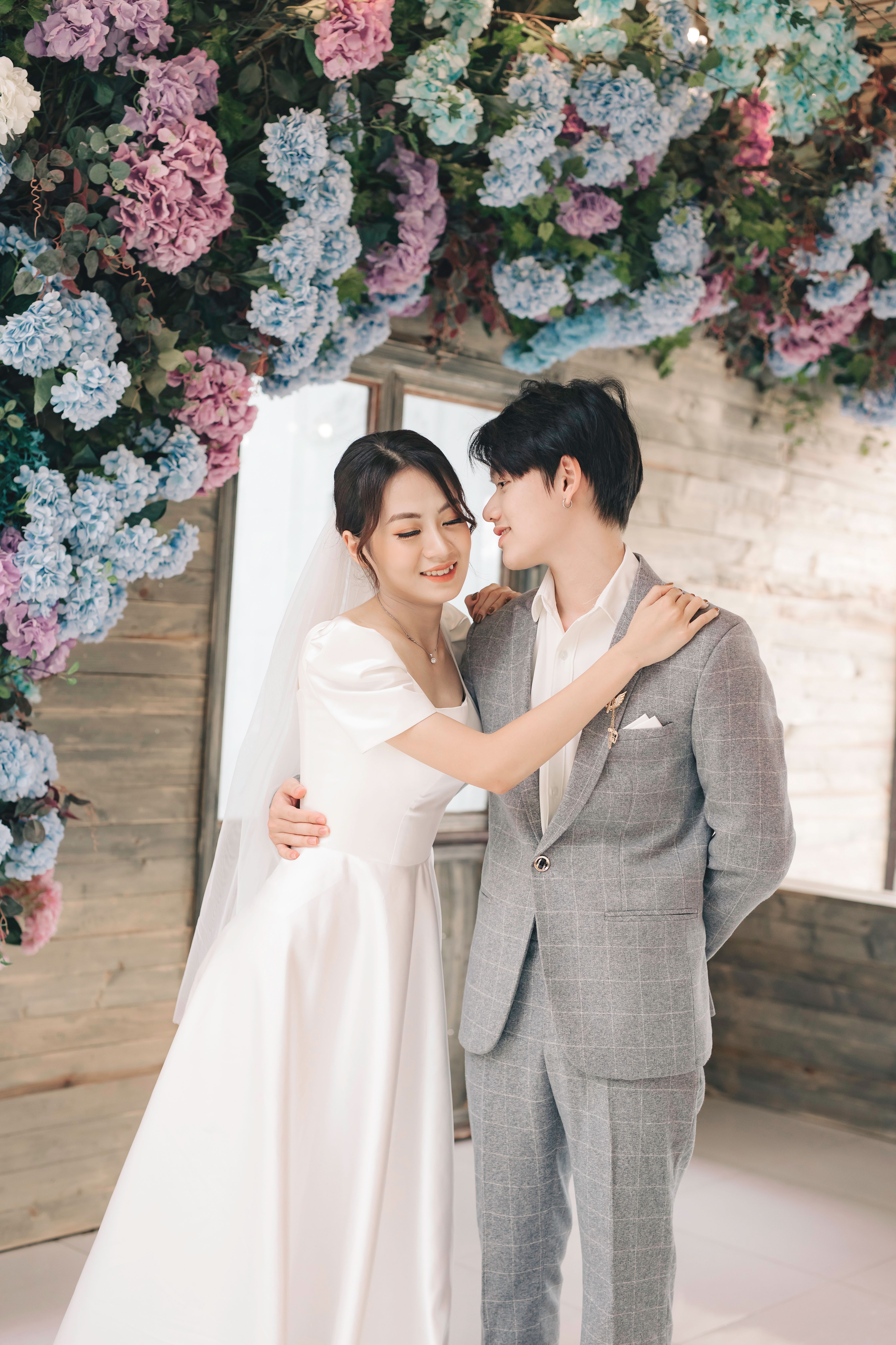 Stunning wedding portrait of an Asian couple with floral backdrop.