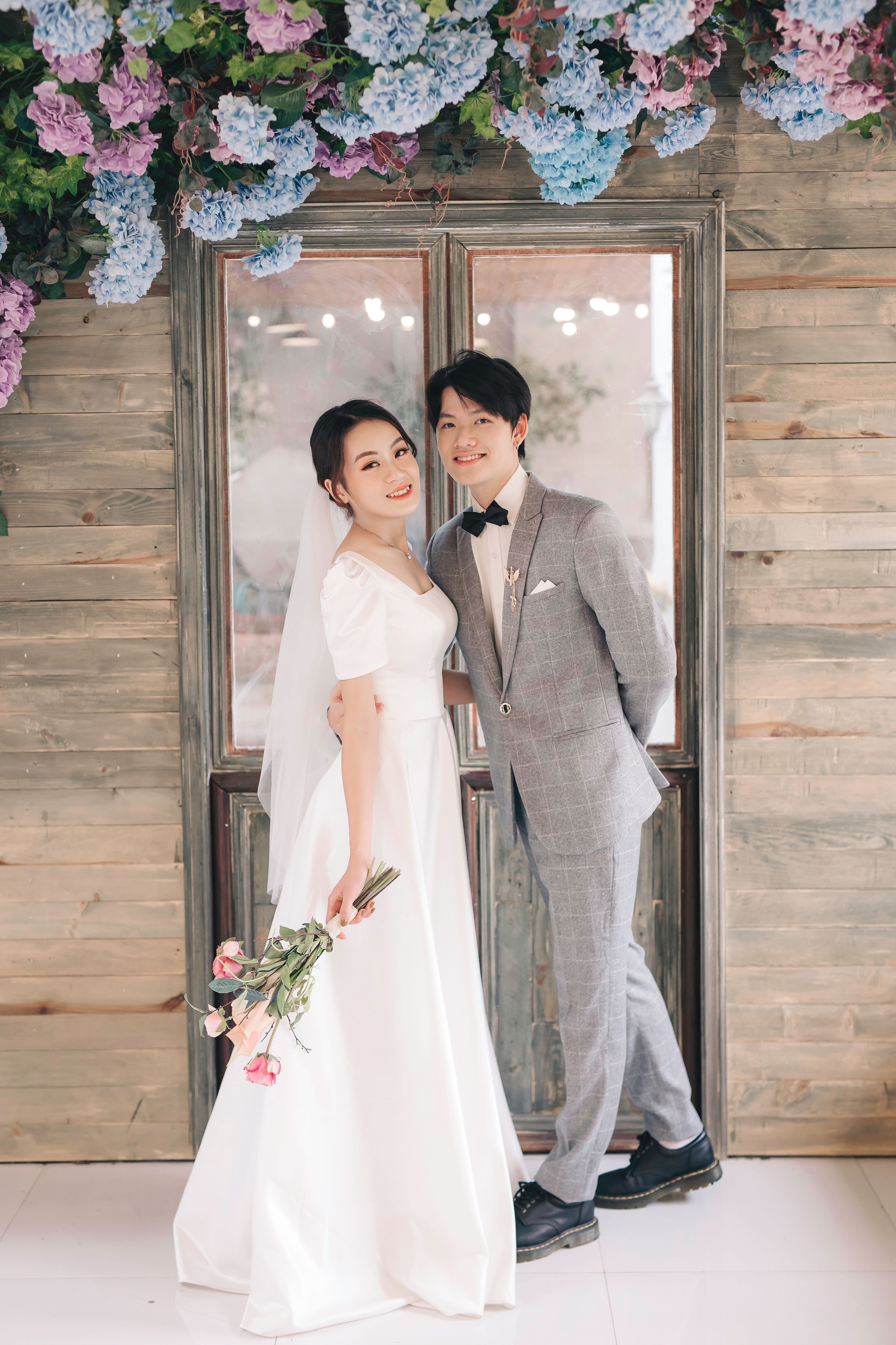 Beautiful portrait of an Asian couple on their wedding day indoors with floral decoration.