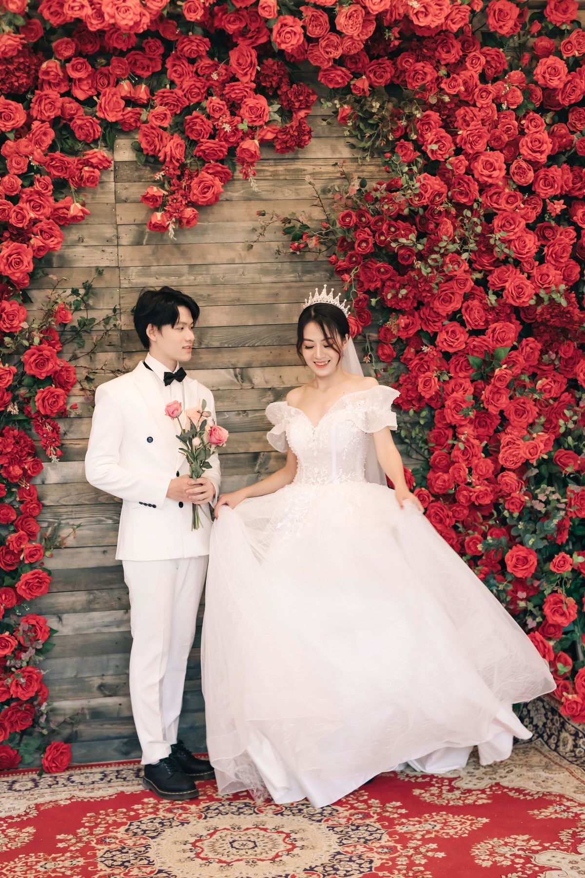 Smiling bride and groom pose under a flower arch on their wedding day
