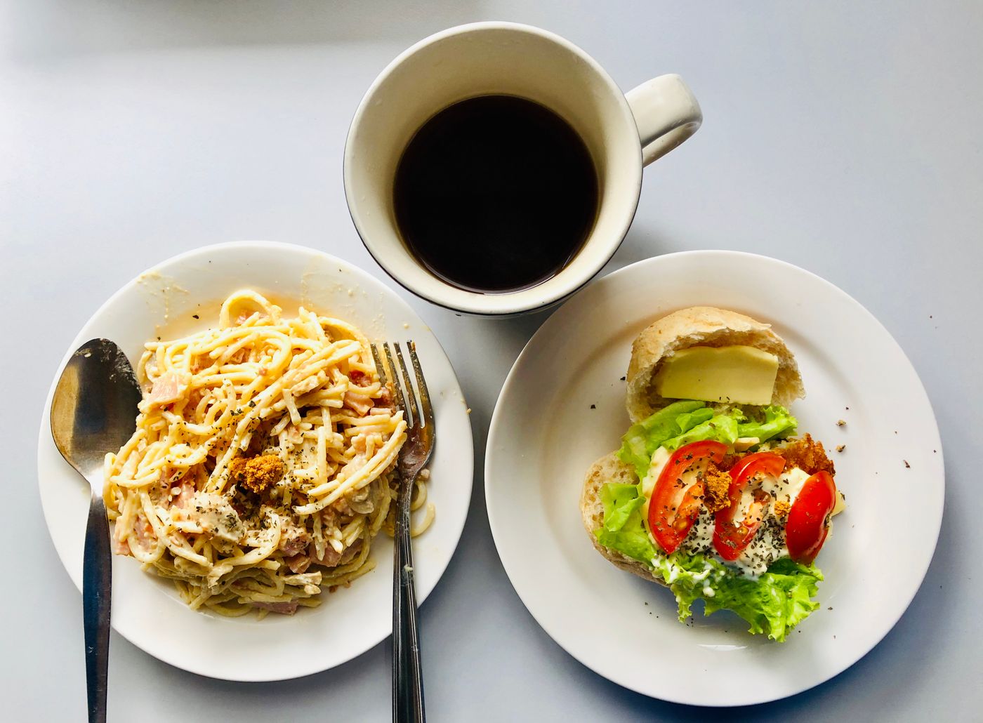 Top view of a delicious breakfast featuring pasta, sandwich, and coffee. Perfect start to the day!