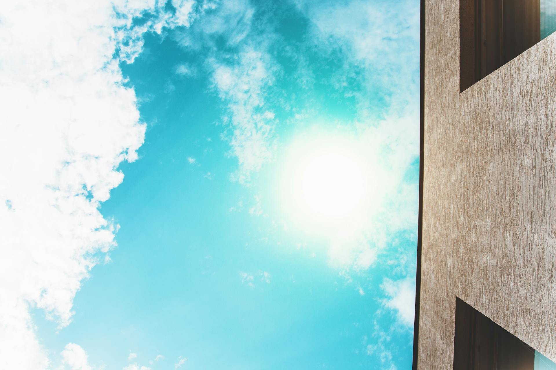 Low angle view of a modern building against a vibrant sunny sky with clouds.