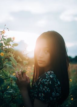 A serene portrait of a woman in a garden during sunset, evoking summer tranquility.