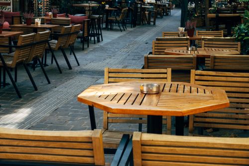 Free A cozy outdoor café scene with wooden tables and chairs, perfect for dining or coffee. Stock Photo