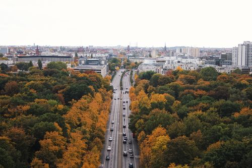 Free Aerial view of Berlin cityscape in autumn with colorful trees lining a busy avenue. Stock Photo