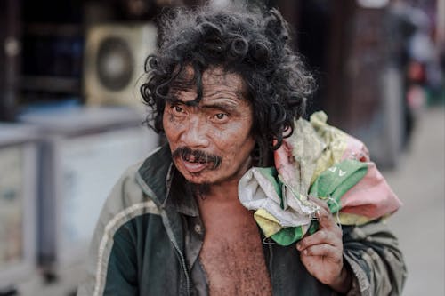 Poor ethnic man with fabric bag on city street