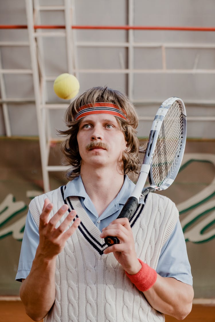 A Man Tossing A Tennis Ball