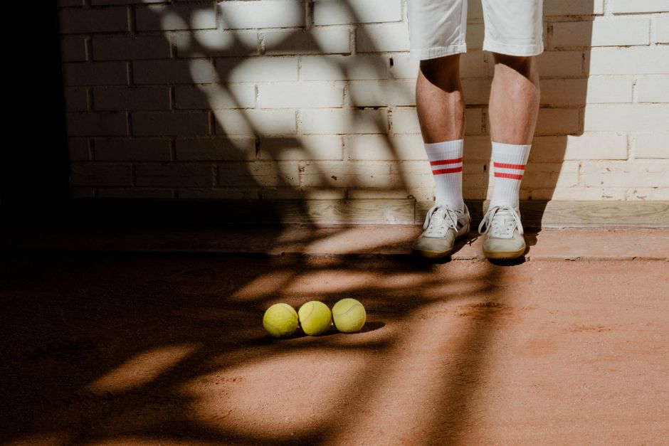 Three tennis balls resting on a clay court