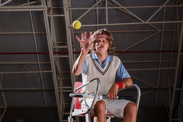 Photo Of A Man In A White Sweater Vest Catching A Tennis Ball