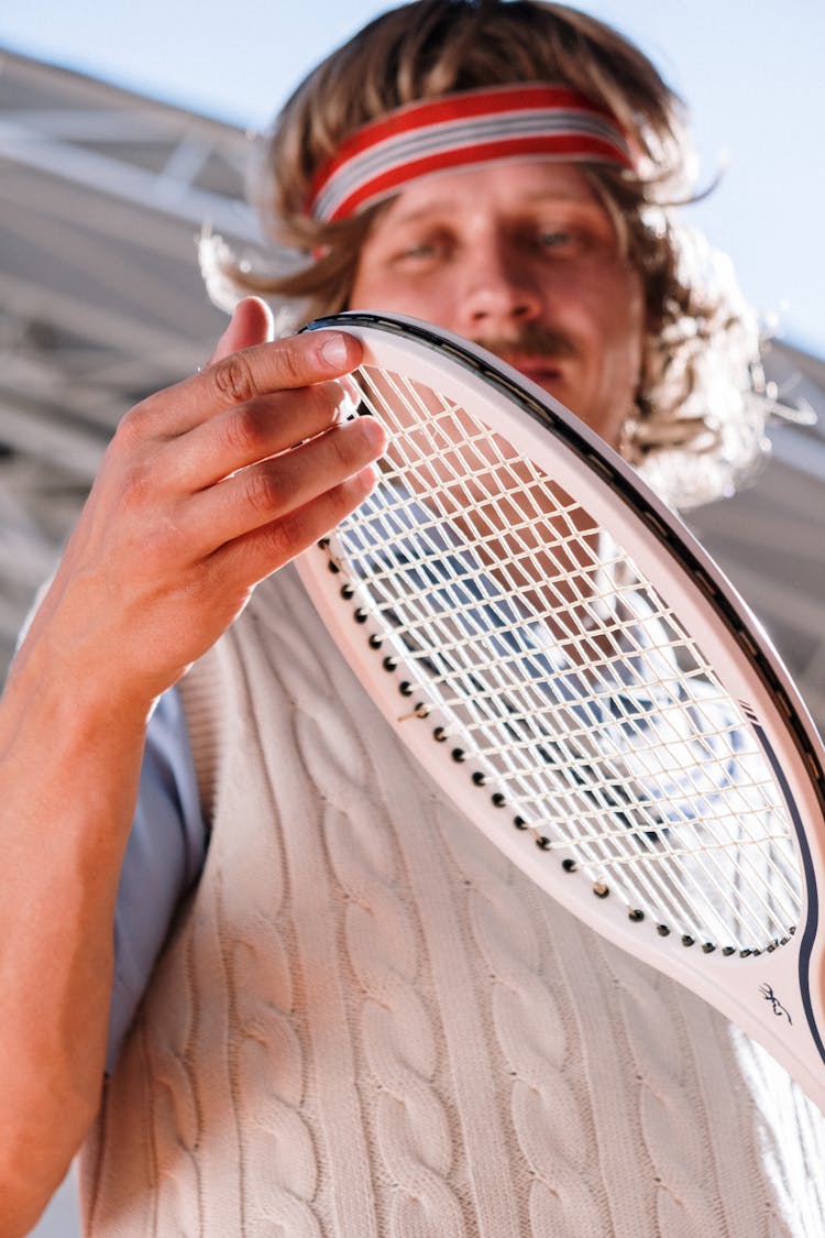 Photo Of A Man With A Red Sweatband Touching His Tennis Racket