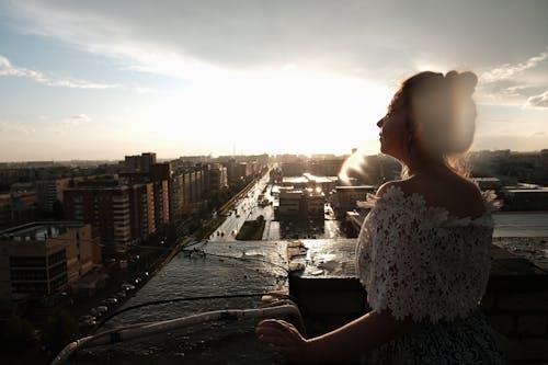 Free Dreamy woman on rooftop near buildings in city under sky Stock Photo