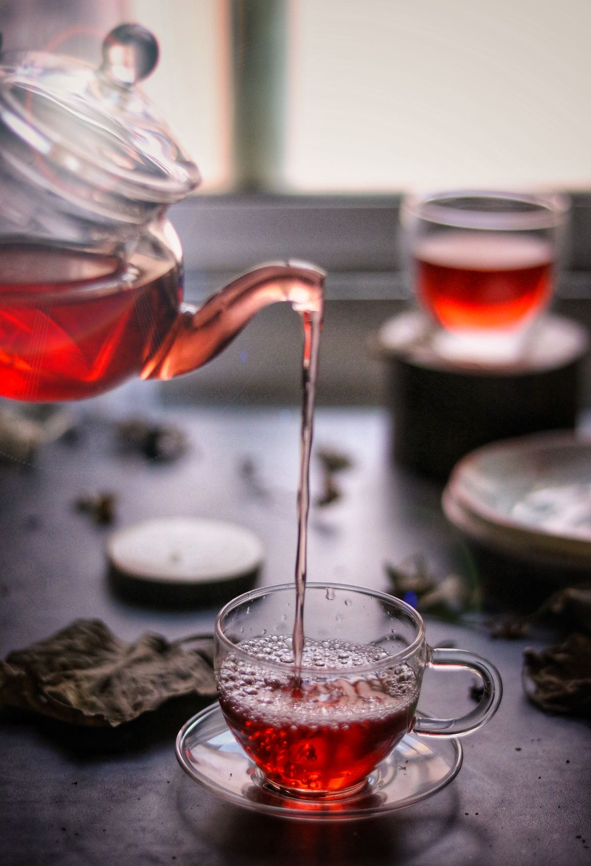 Warm tea being poured into an elegant glass cup