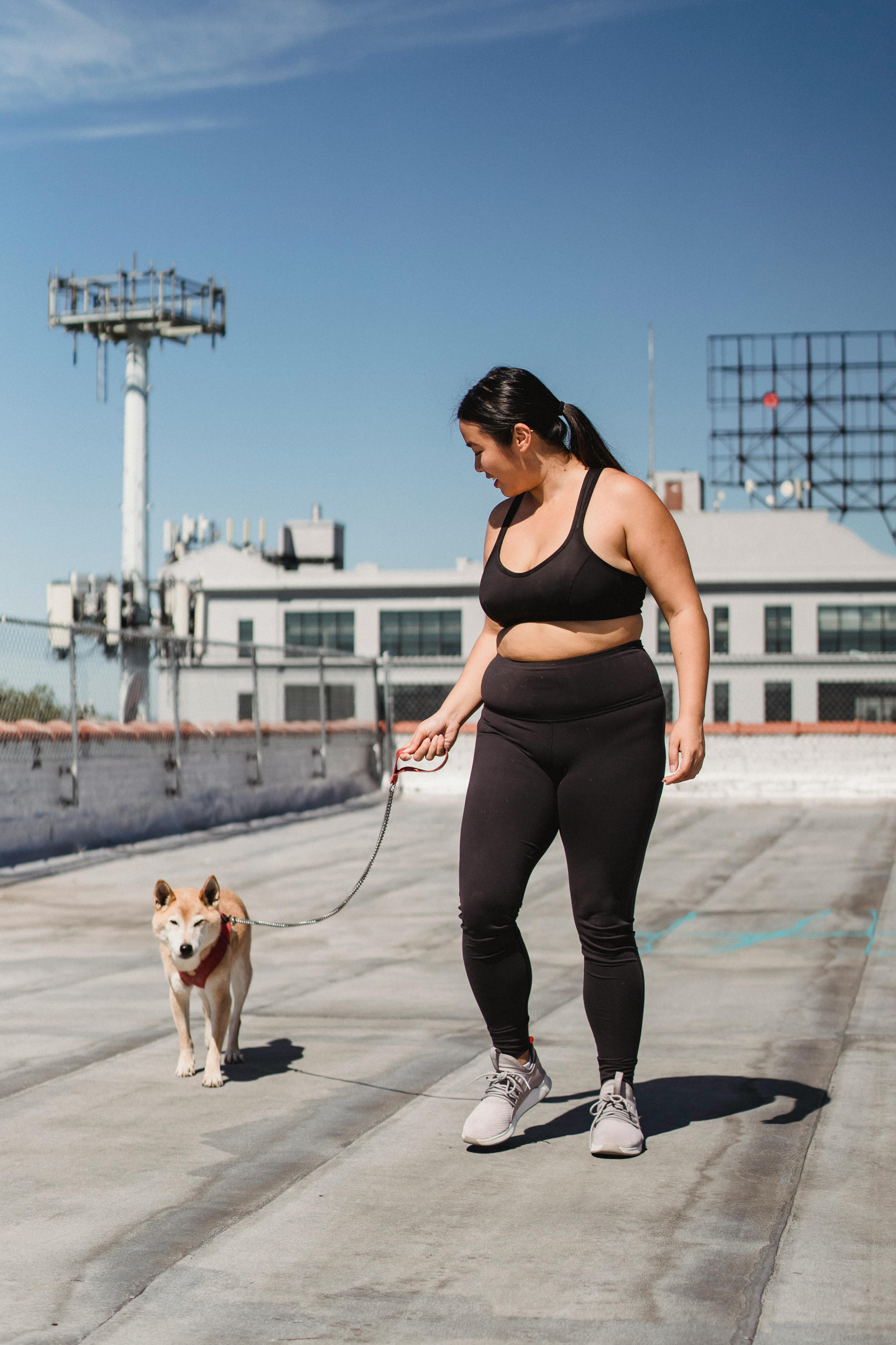 overweight asian woman walking with shiba inu on pier