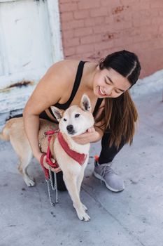 在一个阳光明媚的日子里，年轻女子快乐地拥抱着一只外面的柴犬