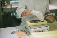 Close-up of a chocolatier adding toppings to a chocolate bar in a confectionery kitchen.