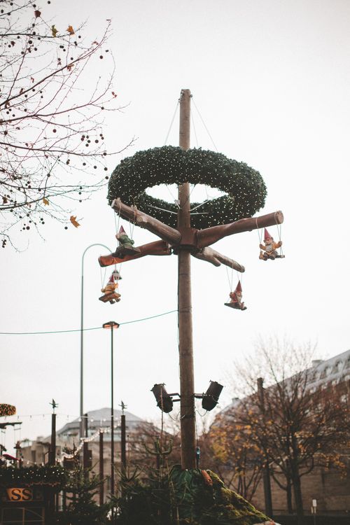 Free Festive Christmas wreath and decorations adorn a wooden pole on a city street in winter. Stock Photo