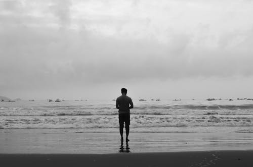 Monochrome Photograph of a Man Standing at the Beach