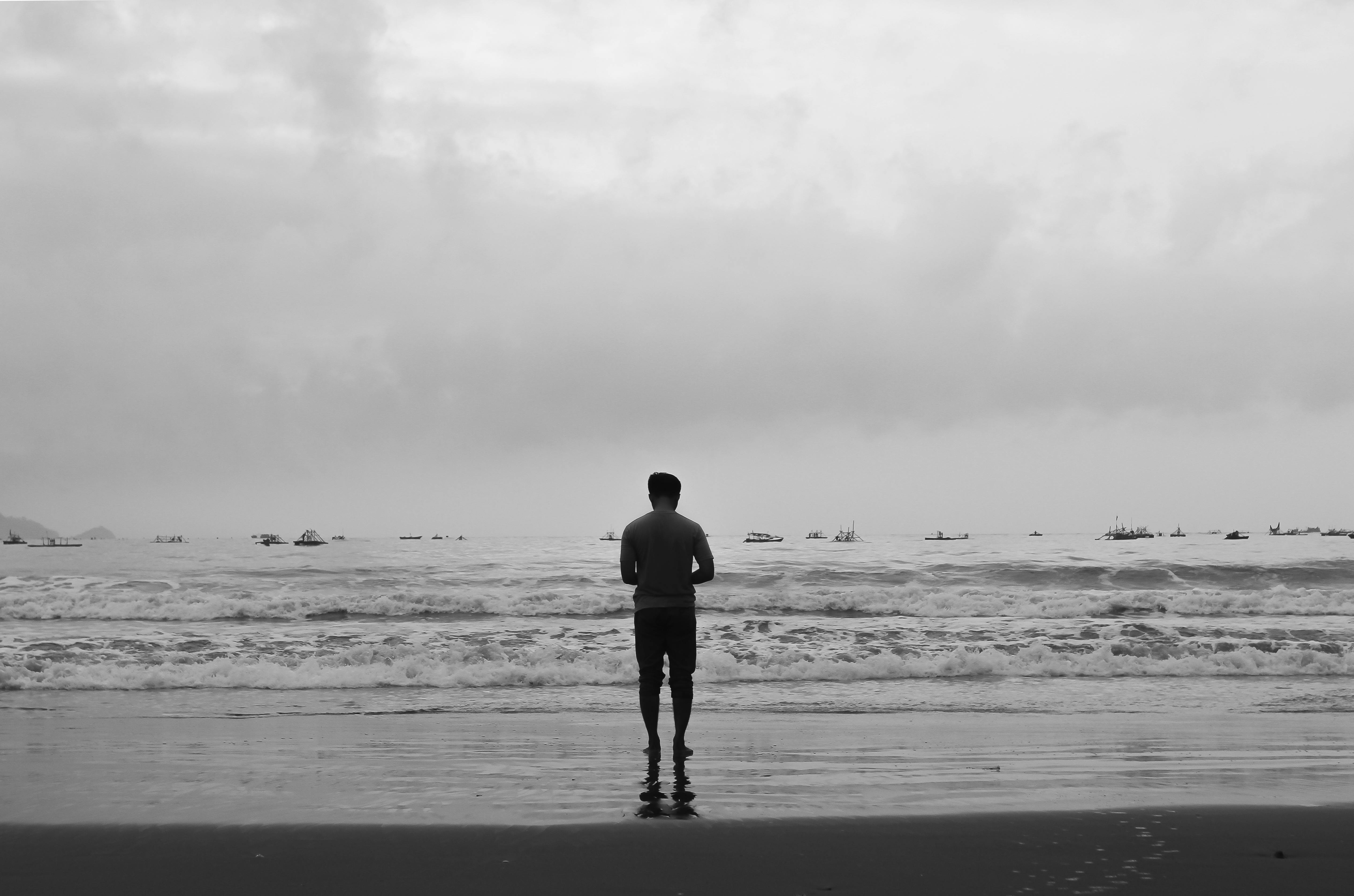 black-and-white-shot-of-a-man-standing-and-looking-at-a-view-free