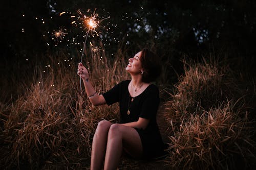 Woman Holding Sparkler While Sitting Down