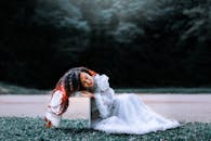 一位身穿优雅白色连衣裙的女子躺在户外草地上，散发着宁静而艺术的气息