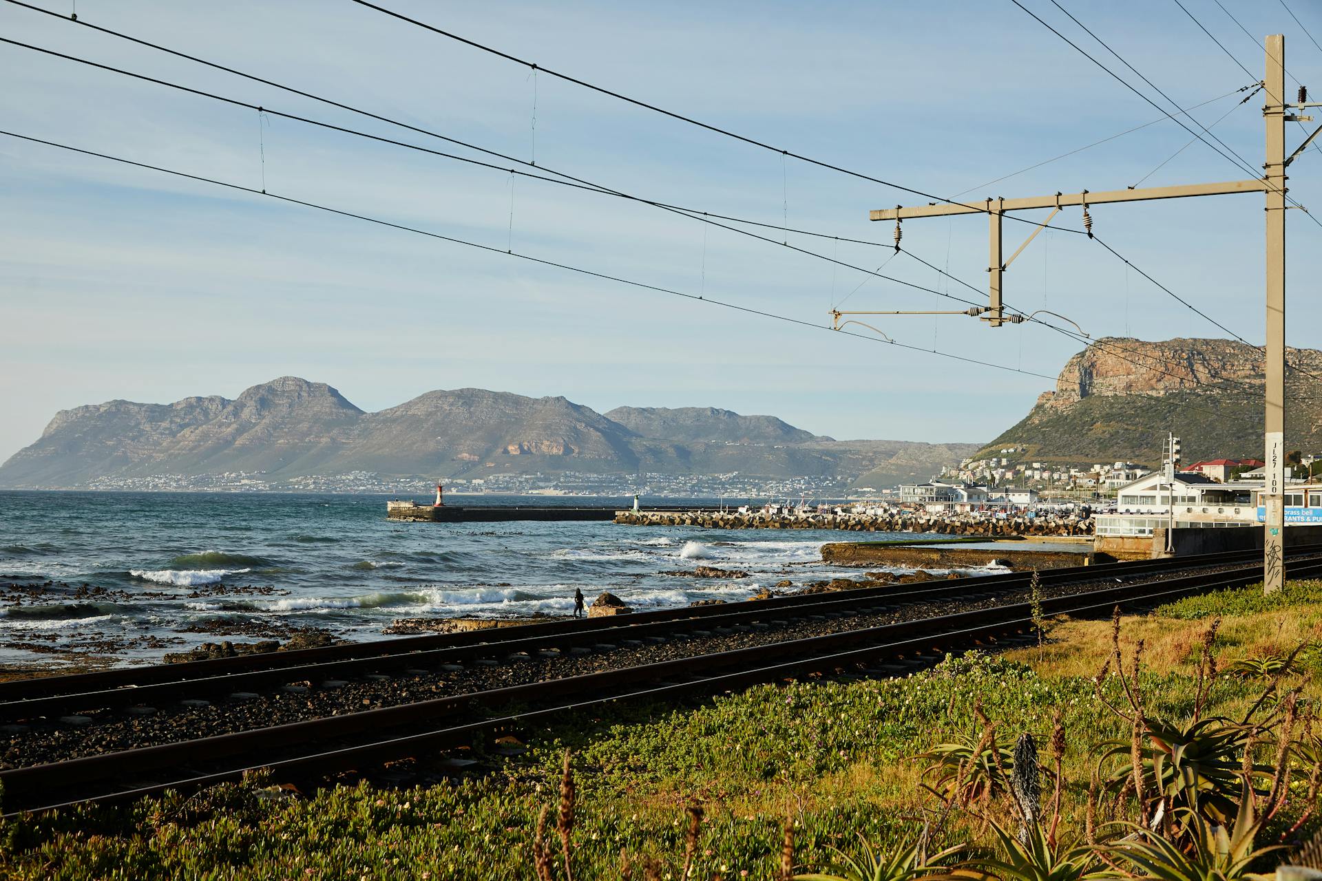Railway tracks along the coastline with mountain backdrop and distant town view