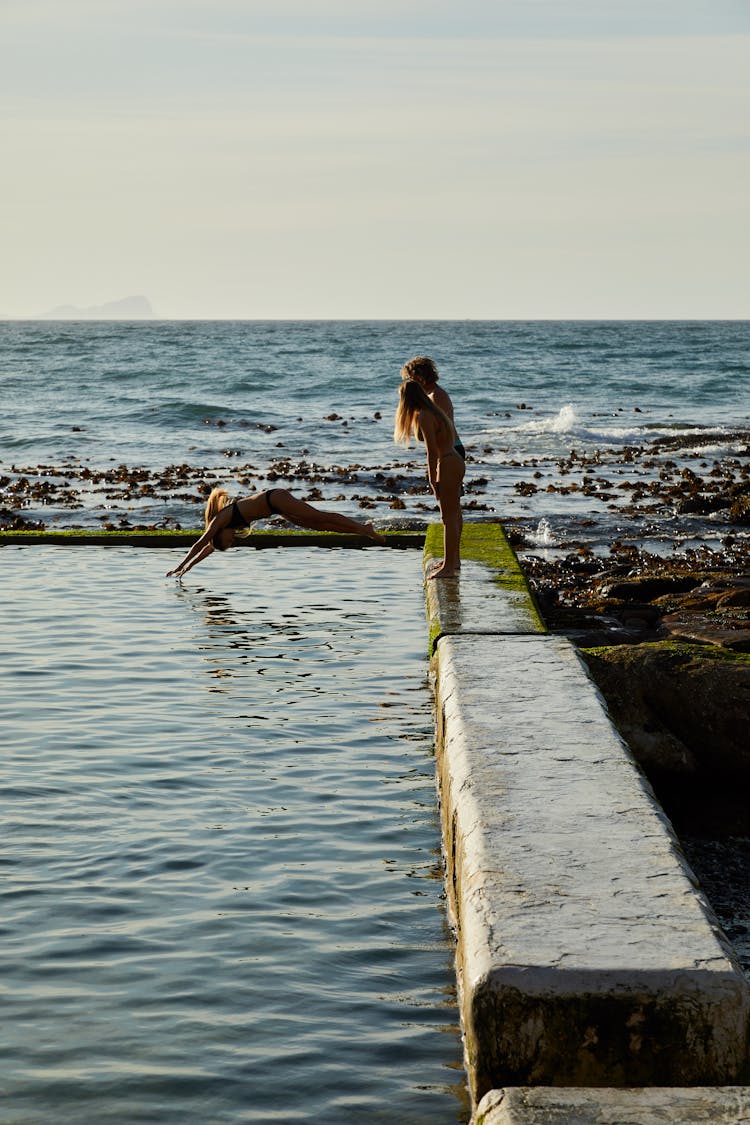 Women Wearing Bikinis Standing And Diving On Water 