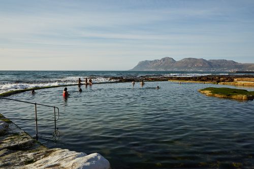 Free People enjoying a natural pool by the ocean with mountains in the background, perfect for nature lovers. Stock Photo