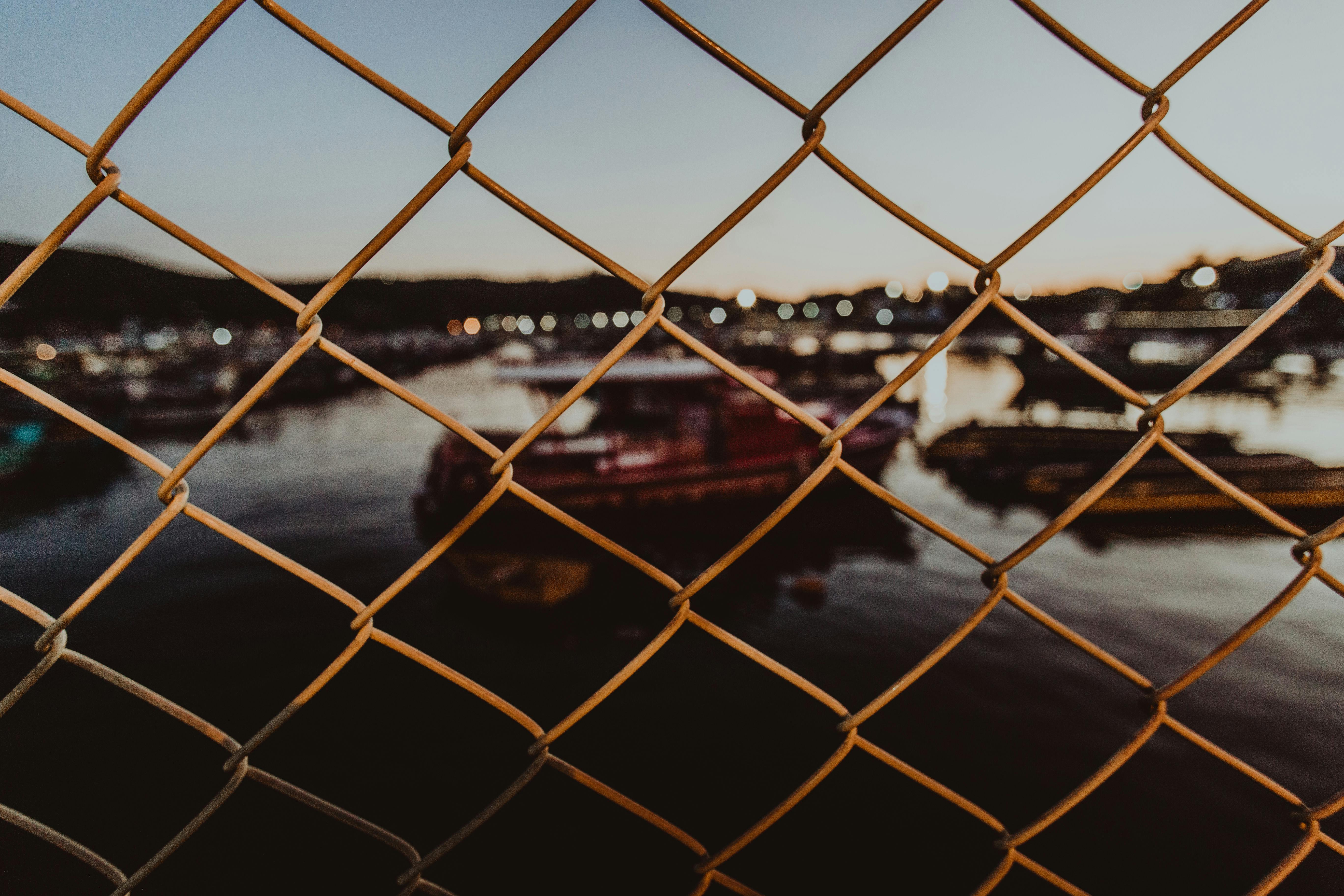through metal mesh fence of city port against evening sky