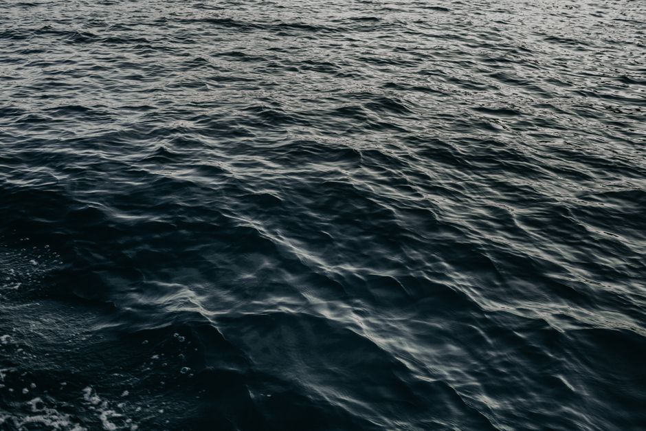 From above of deep blue waving ocean with rippling surface on sunny day
