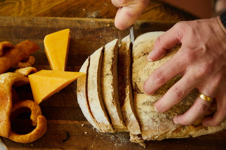 Person Cutting Fresh Bread On Board