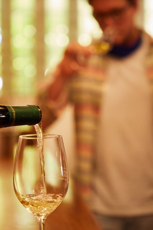 Close-Up Photo of Pouring Champagne on a Champagne Glass