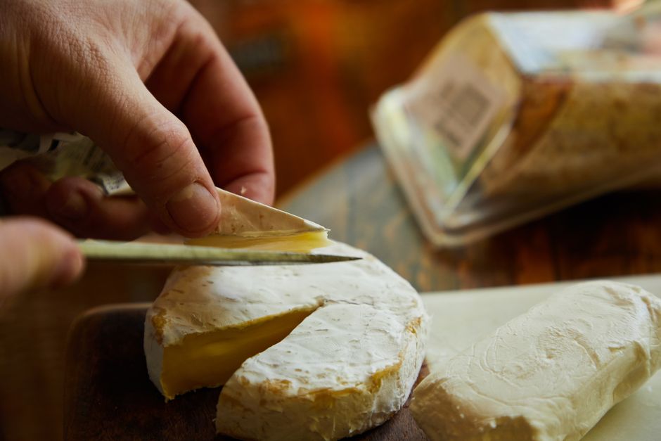 Quesos blandos franceses en tabla de madera con hierbas aromáticas