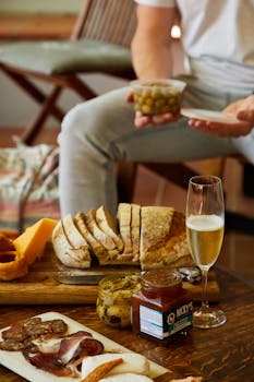 A rustic setup featuring bread, cheese, charcuterie, and champagne, ideal for gourmet gatherings.