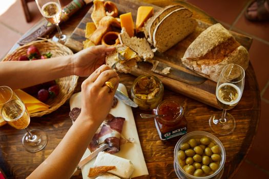 A Person Holding a Bread and a Spoon with Dip Near the Table with Food
